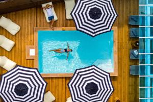 a person swimming in a swimming pool with umbrellas at The Tint At Phuket Town - SHA Plus in Phuket