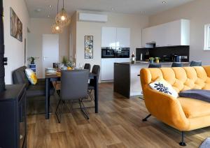 ein Wohnzimmer und eine Küche mit einem Tisch und einem gelben Sofa in der Unterkunft Floatinghouses BernsteinResort in Ribnitz-Damgarten