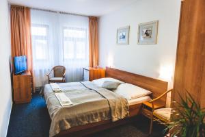 1 dormitorio con 1 cama, 2 sillas y TV en Hotel u České koruny en Hradec Králové