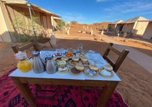 una mesa con comida y jarras de zumo de naranja. en Titanic Merzouga Camp en Merzouga