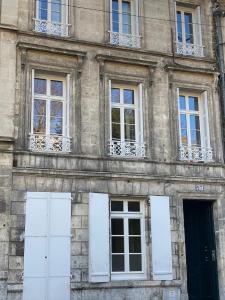 um edifício de pedra com portas e janelas brancas em Golf & Rempart em Angoulême