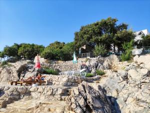 a group of chairs and umbrellas on a rocky beach at Luxury Seaside Holm Oak Villa with Private Beach in Bar