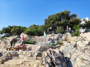 een groep stoelen en parasols op een rotsachtig strand bij Luxury Seaside Holm Oak Villa with Private Beach in Bar