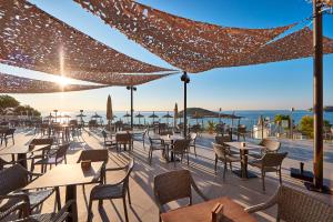 a restaurant with tables and chairs and the ocean at Hotel Florida Magaluf - Adults Only in Magaluf