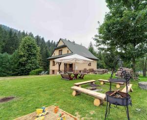 ein Haus mit einem Picknicktisch und einem Grill im Hof in der Unterkunft Leśny Domek in Obidowa