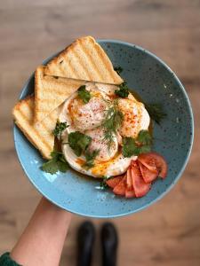 a person holding a plate with eggs and toast at Hotel & Cafe SokoLOVE in Sokolov