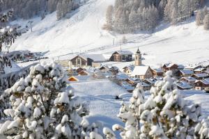 un village recouvert de neige avec une montagne dans l'établissement Genziana - Happy Rentals, à Livigno