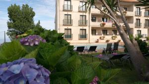un hotel con sillas y flores frente a un edificio en Hotel Oca Vermar, en Aios
