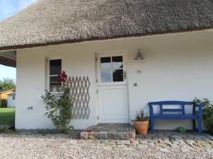 a white cottage with a thatch roof and a blue bench at Ferienhaus Fritid in Groß Schwansee