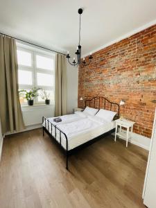a bedroom with a bed and a brick wall at Chabrowy - Apartamenty Smart Projekt in Tarnów