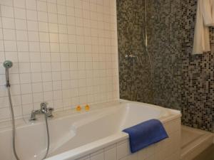 a bath tub with a shower and a blue towel at Fischerhaus Whg Sommerbrise in Neukloster
