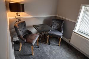 two chairs and a table and a lamp in a room at Glenberis in Hunstanton