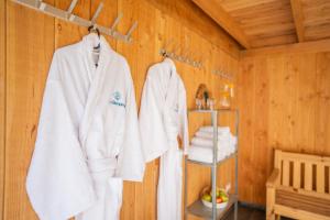 ein Zimmer mit weißen Handtüchern, die an einer Holzwand hängen in der Unterkunft Green Tiny House with shared pool in Zeewolde