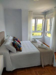 a bedroom with a large bed with two windows at La Marina Posada de LLanes VUT-3648-AS in Posada de Llanes