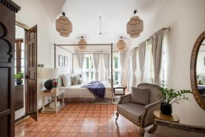 a bedroom with a bed and a chair and a mirror at LohonoStays Castello Villa 5 in Vagator +23 photos