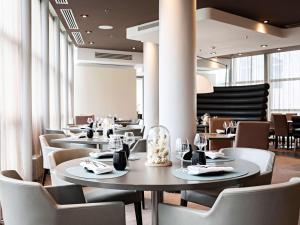 a dining room with tables and chairs and windows at Pullman Paris La Défense in Courbevoie