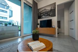 d'un salon avec une table, des livres et une télévision. dans l'établissement Apartament LUX 4 Cieplice, à Jelenia Góra