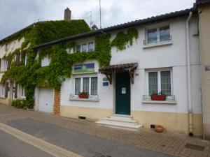 a white building with a green door and ivy at Les Chambres De Solgne in Solgne