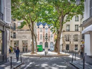 uma mulher andando por uma rua da cidade com árvores em Clara - Modern Loft Sorbonne Notre-Dame Historic em Paris