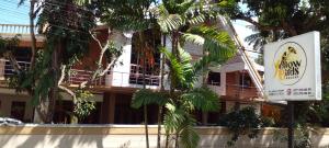 a sign in front of a building with a palm tree at Yellow Birds Resort in Anuradhapura