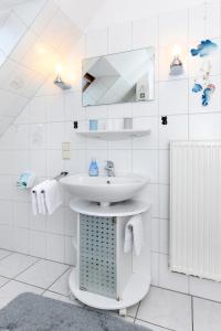 uma casa de banho branca com um lavatório e um espelho em Ferienhaus Dat Krebs Huus em Dornumersiel