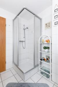 um chuveiro com uma porta de vidro na casa de banho em Ferienhaus Dat Krebs Huus em Dornumersiel