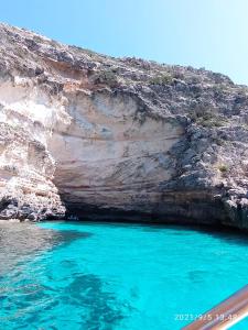 une piscine d'eau bleue à côté d'une falaise rocheuse dans l'établissement Apartamento Illa Blanca, à Es Pujols