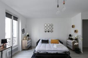 um quarto branco com uma cama e uma grande janela em Paris - Studio - Pere-Lachaise em Paris