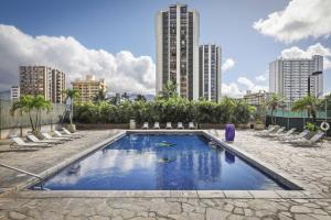 une piscine avec des chaises et des bâtiments en arrière-plan dans l'établissement Aston Waikiki Sunset, à Honolulu