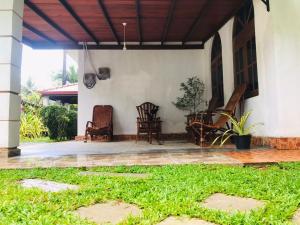 a porch of a house with chairs andgrass at Surewo Sun Shine Apartment in Bentota
