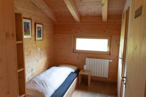 Bett in einem kleinen Zimmer mit Fenster in der Unterkunft Berghaus Sulzfluh in St. Antönien