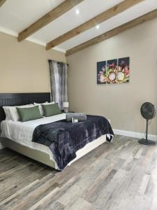 a bedroom with a large bed and wooden floors at Tsitsikamma Garden Chalets in Stormsrivier