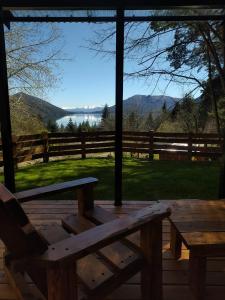 a wooden bench on a deck with a view of the water at Tiny House Melgarejo in San Carlos de Bariloche