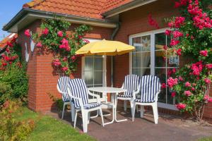 uma mesa e cadeiras com um guarda-sol num pátio em Ferienhaus Dat Krebs Huus em Dornumersiel