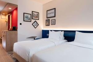 two beds in a hotel room with white sheets at Hampton By Hilton Budapest City Centre in Budapest