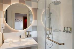 a bathroom with a sink and a shower with a mirror at Hampton By Hilton Budapest City Centre in Budapest
