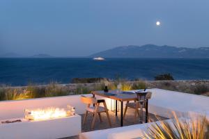 une terrasse avec une table et des chaises et l'océan dans l'établissement KOIA All - Suite Well Being Resort - Adults Only, à Ágios Fokás