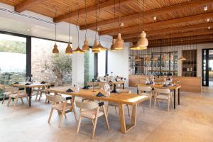 a restaurant with wooden tables and chairs and windows at KOIA All - Suite Well Being Resort - Adults Only in Ágios Fokás