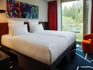 a large bed in a hotel room with a window at TRIBE Baden-Baden in Baden-Baden