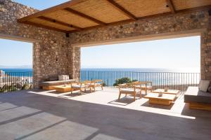 un patio con mesas y sillas y vistas al océano en KOIA All - Suite Well Being Resort - Adults Only, en Ágios Fokás