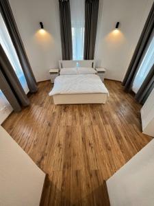 a bedroom with a bed and wooden floors and windows at Hotel & Cafe SokoLOVE in Sokolov