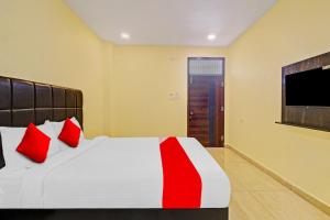 um quarto com uma cama com almofadas vermelhas e uma televisão em Lakshmi Royal Inn em Warangal