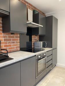 a kitchen with stainless steel appliances and a brick wall at Manchester City luxury hideaway in Urmston