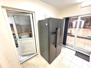 een roestvrijstalen koelkast in een kamer met 2 ramen bij Lucky Fives at Castle Road in Birmingham