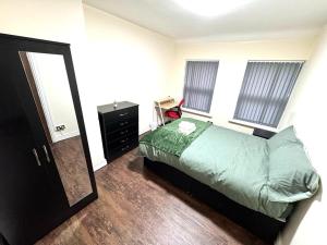 a bedroom with a bed and a dresser and windows at Lucky Fives at Castle Road in Birmingham