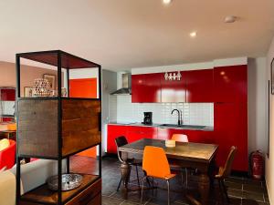 une cuisine avec des placards rouges, une table et des chaises dans l'établissement Rêve Perdu / studio PJ, à Bruges