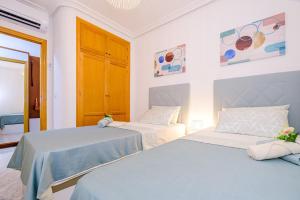 due letti in una stanza con pareti bianche di Home&Holiday Goleta with parking-option a Torrevieja