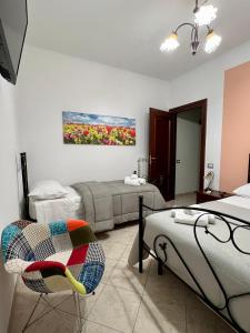 Habitación con 2 camas, una silla y una pintura en a casa di Ale, en Santa Maria di Castellabate