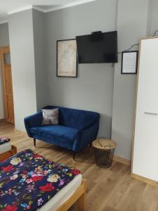 a living room with a blue couch and a flat screen tv at Kwatery u Jarka in Jelenia Góra