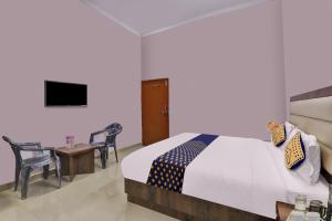 a bedroom with a bed and a table and a television at SPOT ON Abhinandan Hotel And Restaurant in Pratāpgarh